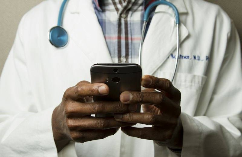 Clinician in a white coat using a smartphone