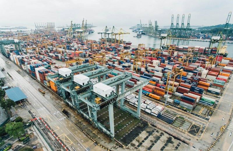 Aerial view of a container port with cranes and stacked shipping containers