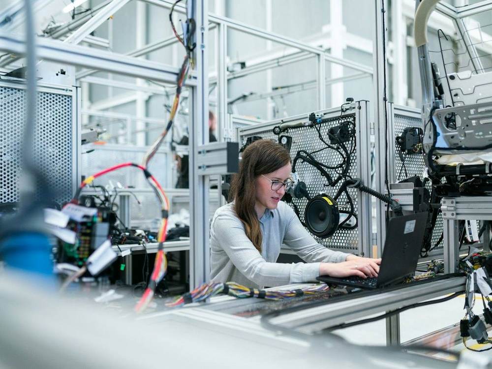 Engineer working on a laptop beside automated production equipment