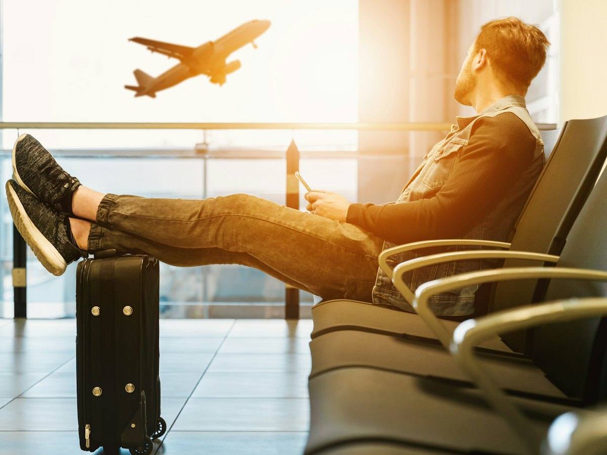 Traveller relaxing in an airport departure lounge as a plane takes off