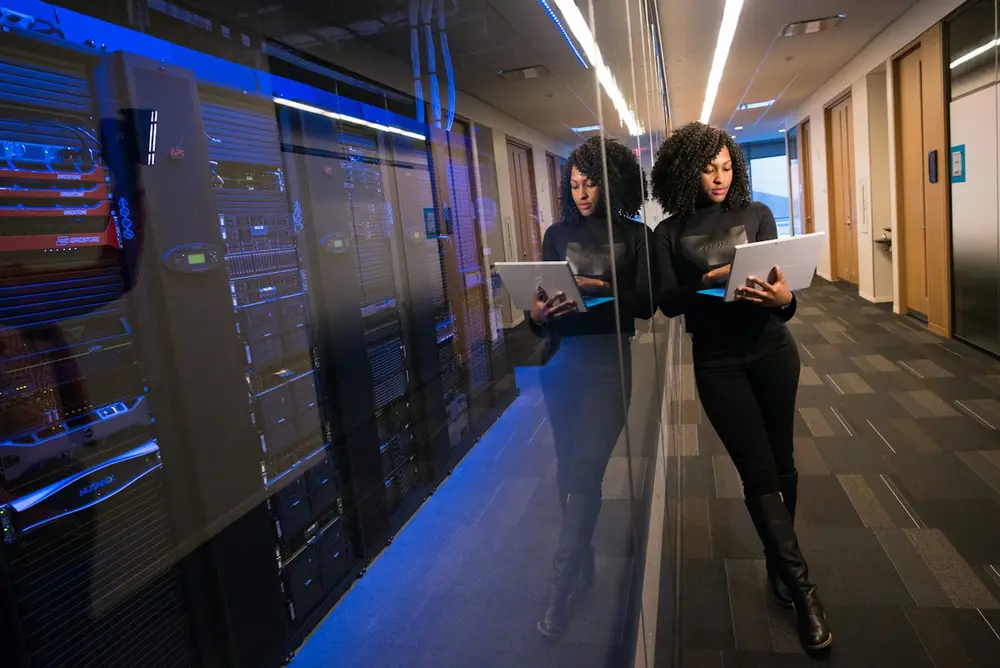 Engineer holding a laptop in a data centre corridor lined with server racks