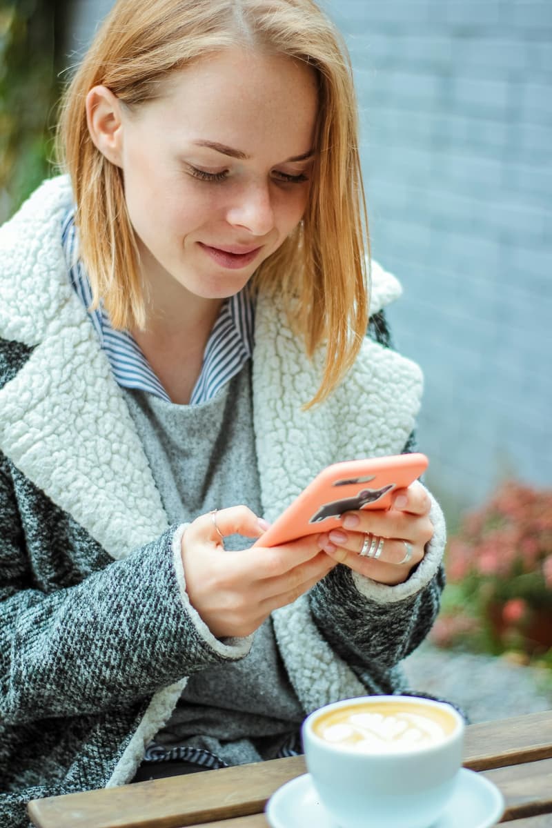 A woman smiling as she reads something on her phone