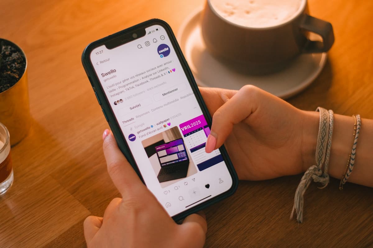 Hands holding a phone open on a social media post, next to a cup of coffee