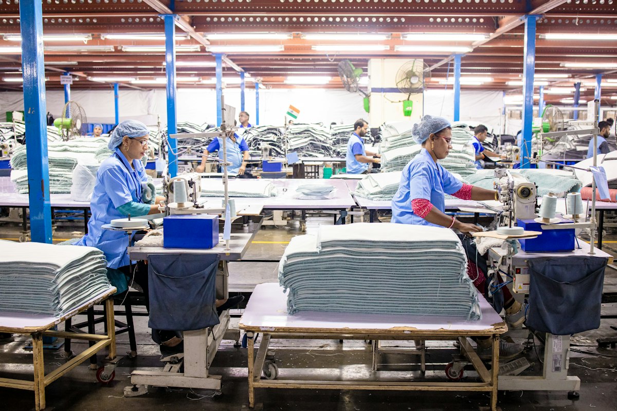 Textile workers sewing fabric at production line workstations