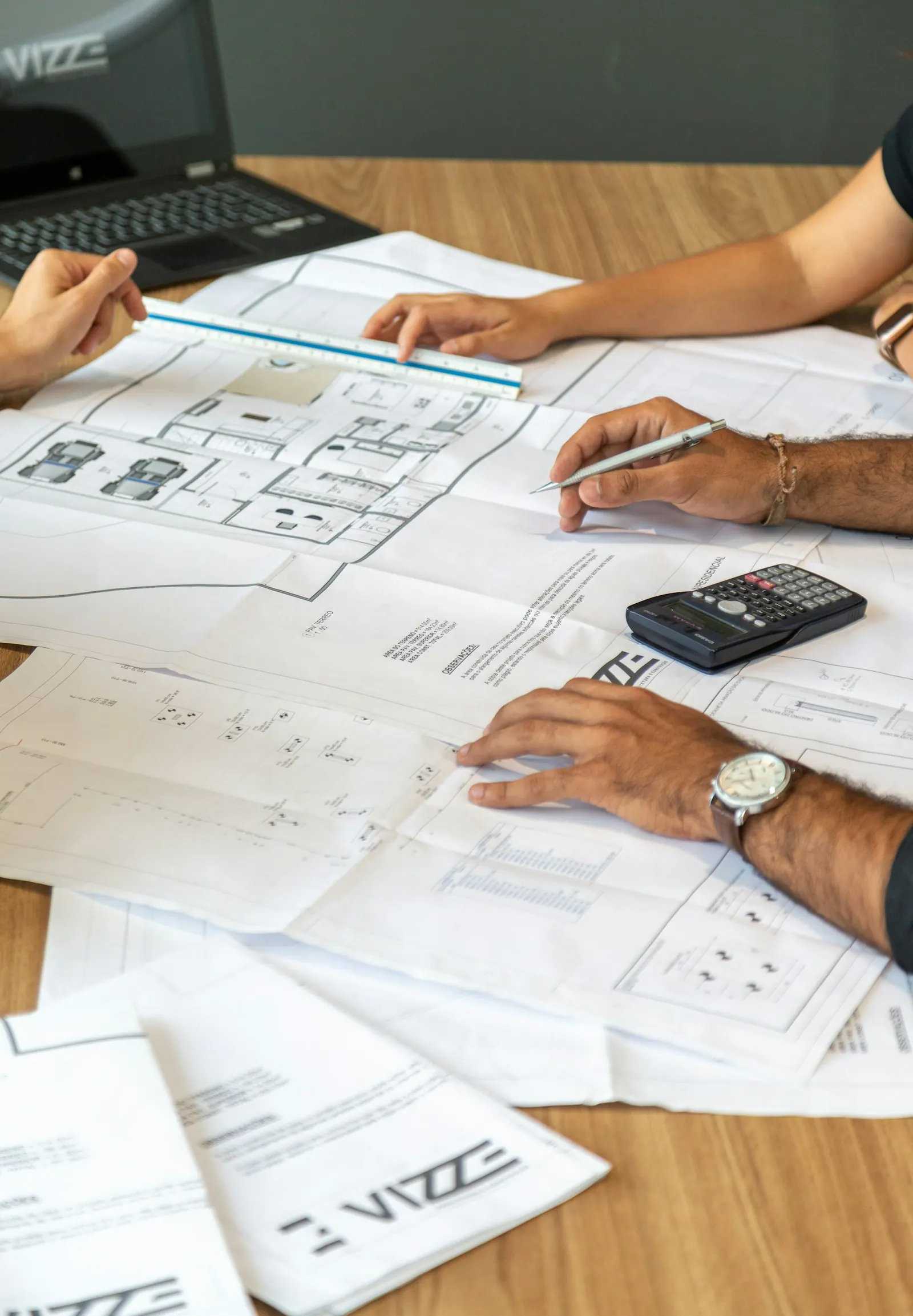 Planners reviewing printed drawings and production paperwork at a desk