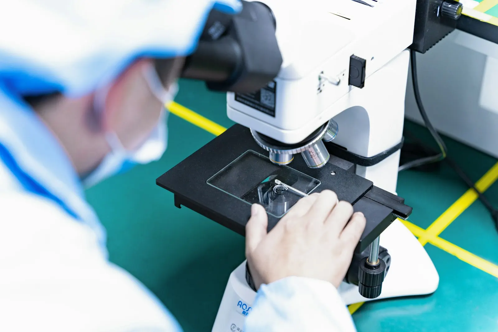 Quality inspector in a lab coat examining a sample under a microscope