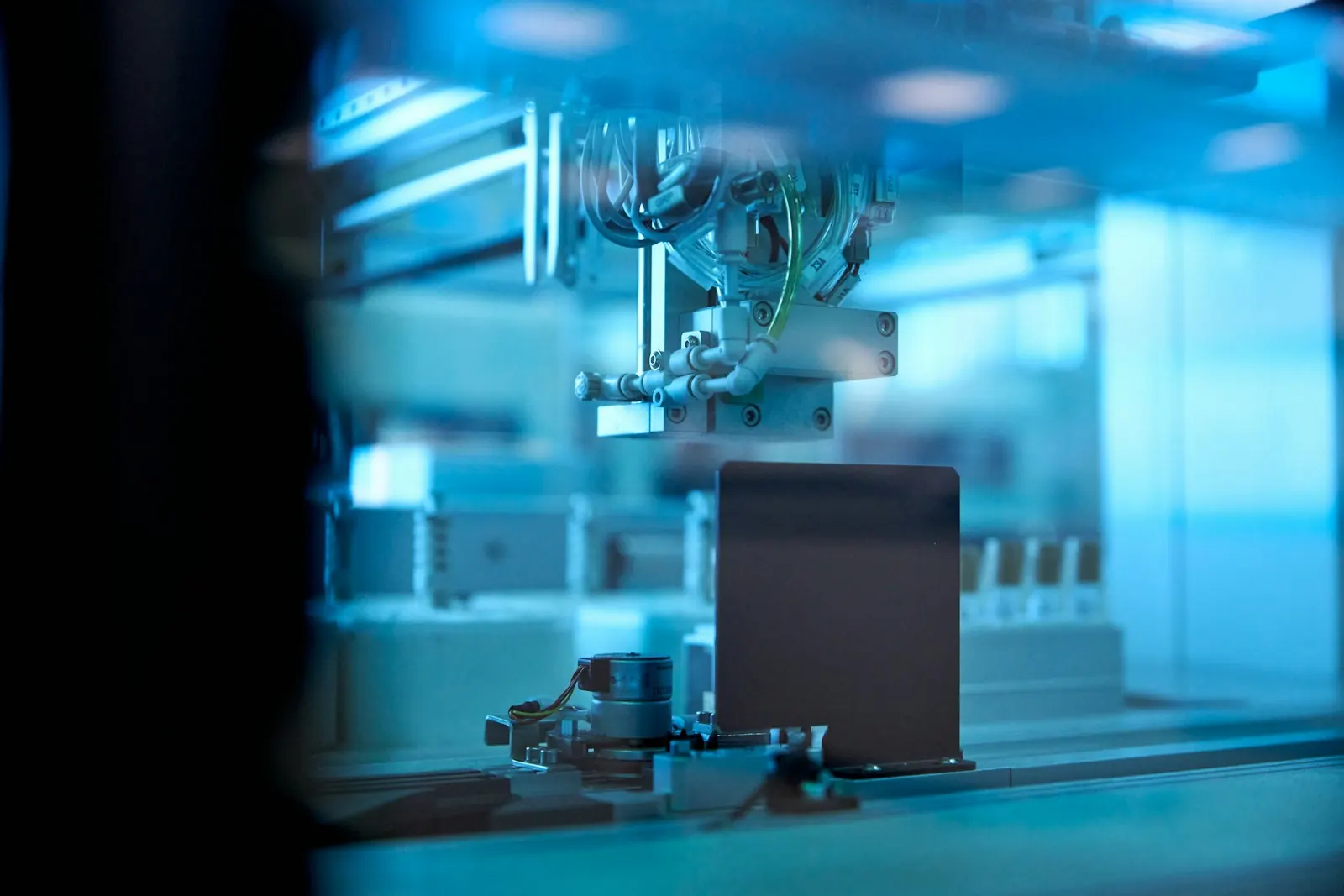 Automated inspection equipment working inside a blue-lit enclosure