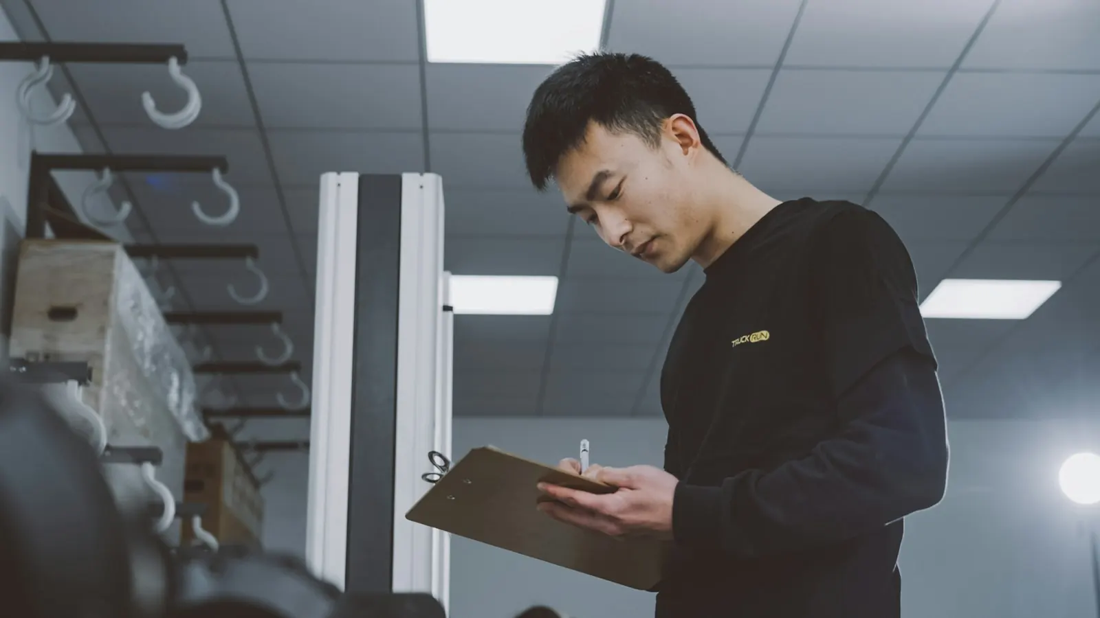 Production supervisor recording work on a clipboard in a factory