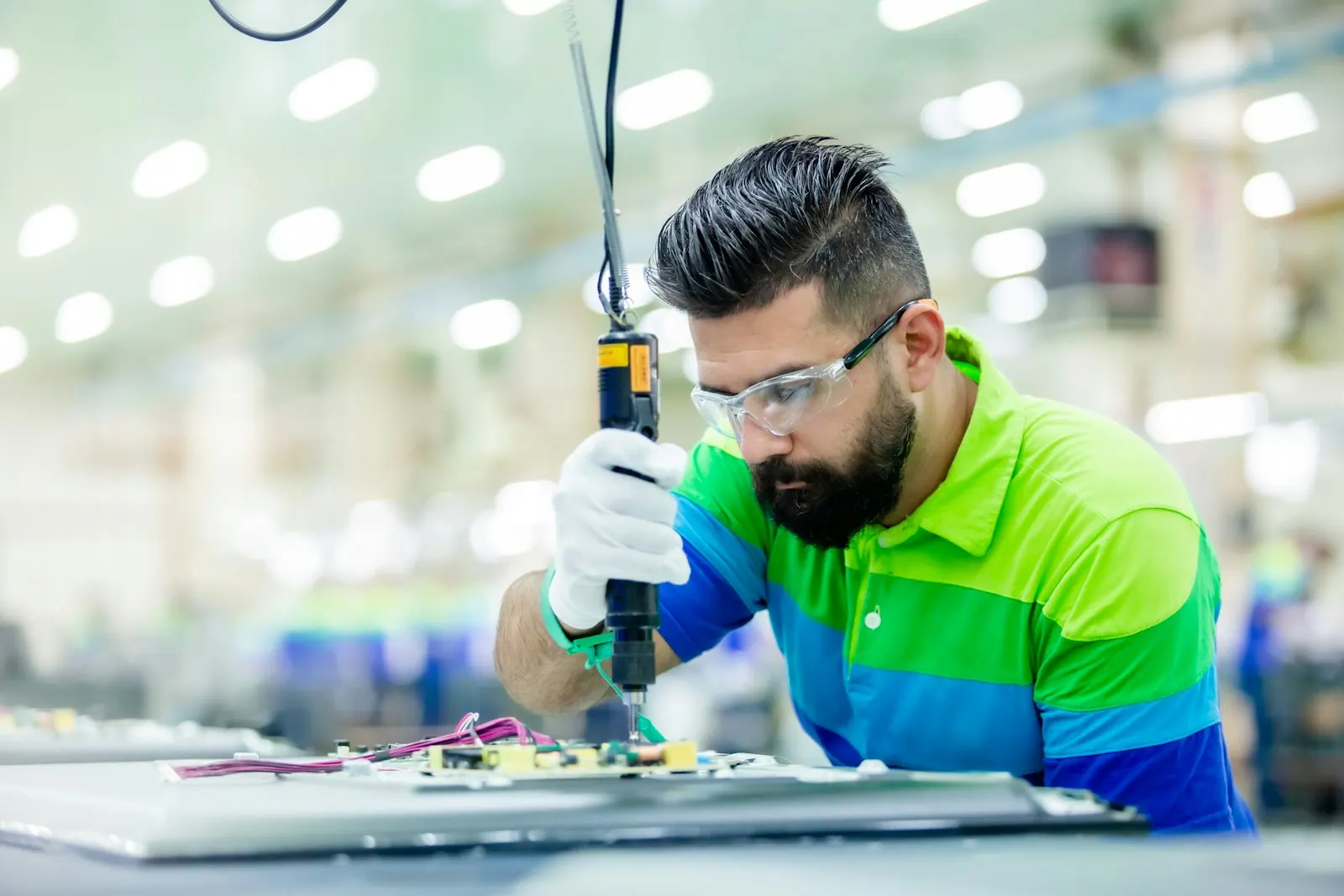 Operator assembling electronics with a screwdriver on a production line