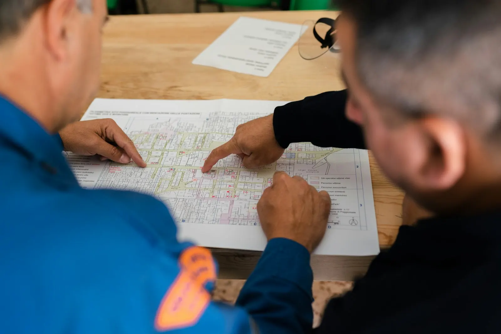 Two plant staff in uniforms reviewing a printed layout plan on a table