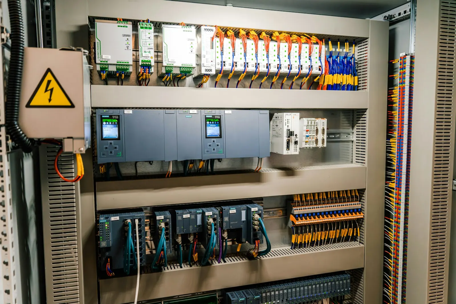 Open electrical control cabinet with PLC modules and wiring